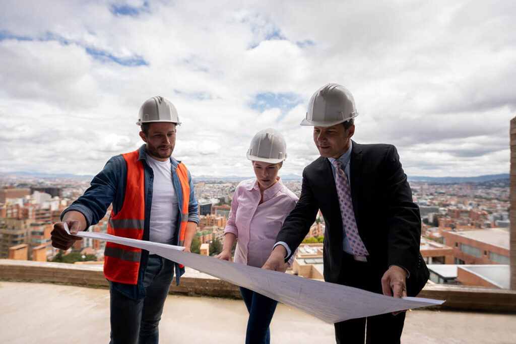 Drei Personen auf einer Baustelle planen die nächsten Schritte hinsichtlich des Ausbaus des Wohnraums